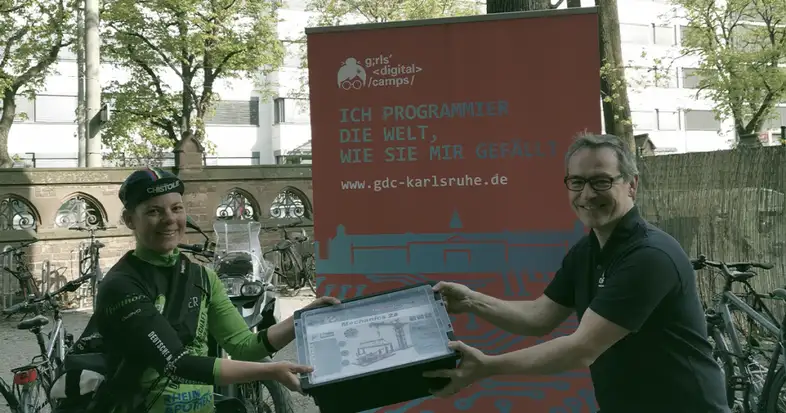 Ein Mann übergibt einen fischertechnik-Baukasten an einen Fahrradkurier. Bild: CyberForum e.V.