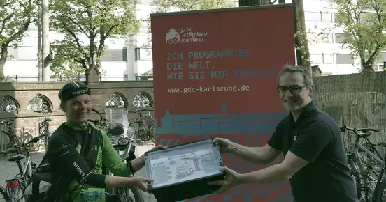 Ein Mann übergibt einen fischertechnik-Baukasten an einen Fahrradkurier. Bild: CyberForum e.V.