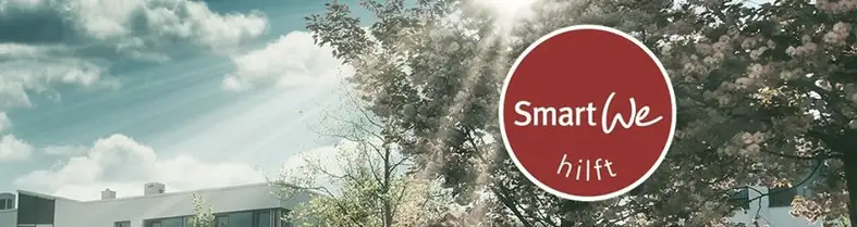 Foto auf dem man blauen Himmel, ein Gebäude und einen blühenden Baum sieht. Im Vordergrund ist ein roter Kreis eingeblendet auf dem steht "SmartWe hilft".